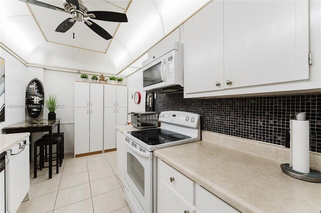 4330 Hillcrest Dr Unit 505, Hollywood, FL 33021 - kitchen with white appliances, a ceiling fan, decorative backsplash, light tile patterned flooring, and white cabinets
