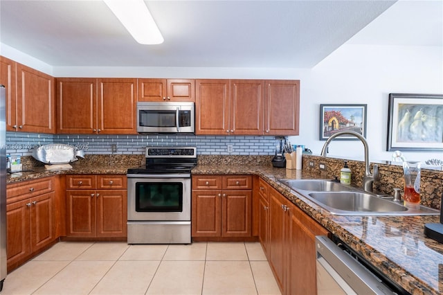 kitchen with stainless steel appliances, a sink, brown cabinets, and light tile patterned flooring