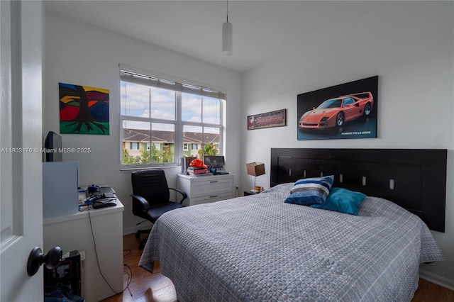 bedroom featuring wood finished floors, baseboards, and a desk