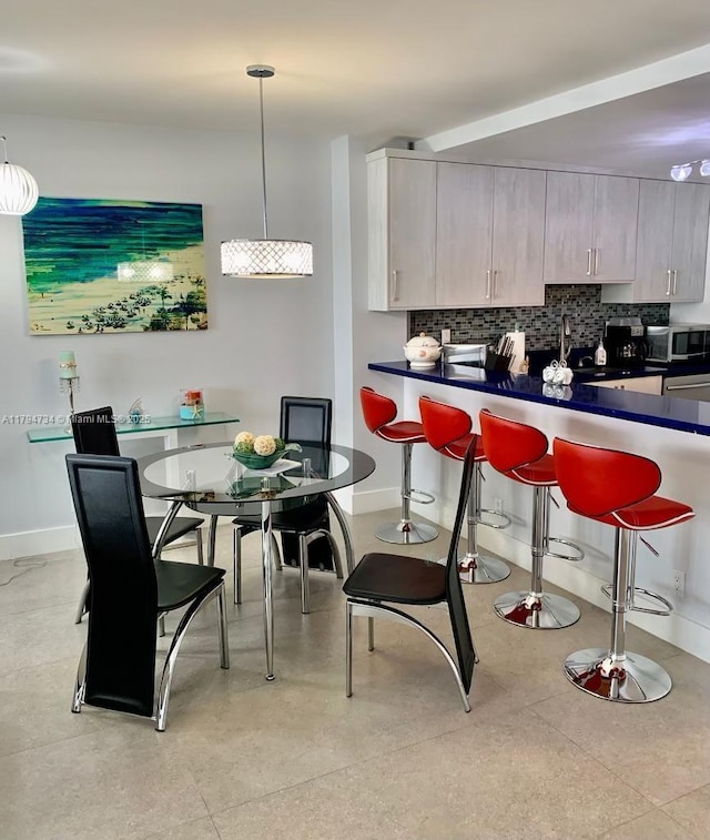 3725 S Ocean Dr Unit 311, Hollywood, FL 33019 - kitchen with stainless steel microwave, dark countertops, a kitchen bar, decorative backsplash, and a sink