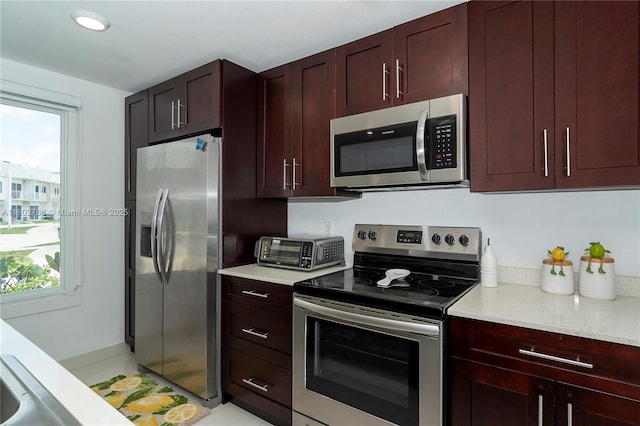 13949 SW 259th Way, Homestead, FL 33032 - kitchen with stainless steel appliances, reddish brown cabinets, light stone countertops, and recessed lighting