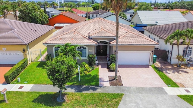 9072 NW 145th St, Miami Lakes, FL 33018 - mediterranean / spanish-style house with a gate, a tiled roof, stucco siding, an attached garage, and decorative driveway