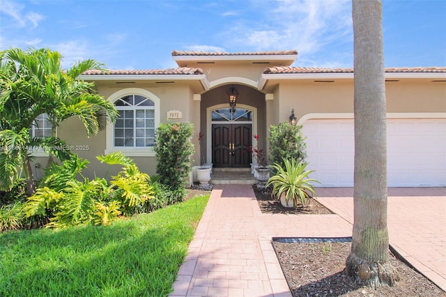 9072 NW 145th St, Miami Lakes, FL 33018 - property entrance with an attached garage, stucco siding, decorative driveway, and a tiled roof