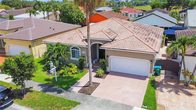 9072 NW 145th St, Miami Lakes, FL 33018 - mediterranean / spanish-style home with an attached garage, stucco siding, decorative driveway, a gate, and a tiled roof
