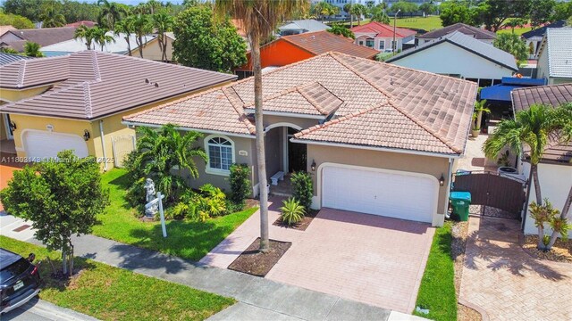 9072 NW 145th St, Miami Lakes, FL 33018 - mediterranean / spanish house with an attached garage, stucco siding, decorative driveway, a gate, and a tiled roof
