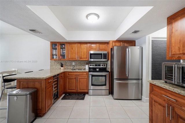 857 W 37th St, Hialeah, FL 33012 - kitchen featuring stainless steel appliances, beverage cooler, a peninsula, and brown cabinets