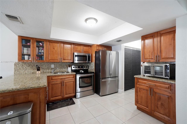 857 W 37th St, Hialeah, FL 33012 - kitchen featuring appliances with stainless steel finishes, a sink, brown cabinets, and decorative backsplash