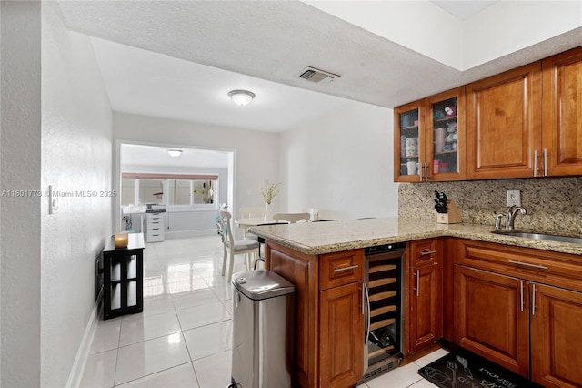 857 W 37th St, Hialeah, FL 33012 - kitchen featuring beverage cooler, brown cabinetry, light tile patterned floors, and decorative backsplash