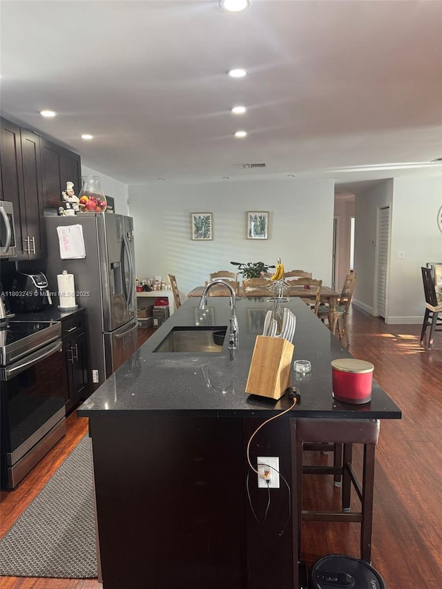 111 SW 24th Ave, Miami, FL 33135 - kitchen with a sink, appliances with stainless steel finishes, a kitchen island with sink, dark wood-style flooring, and a kitchen breakfast bar