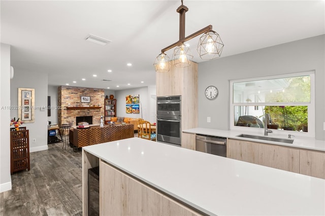 6809 Mentone St, Coral Gables, FL 33146 - kitchen featuring light brown cabinetry, a sink, stainless steel appliances, modern cabinets, and a large fireplace