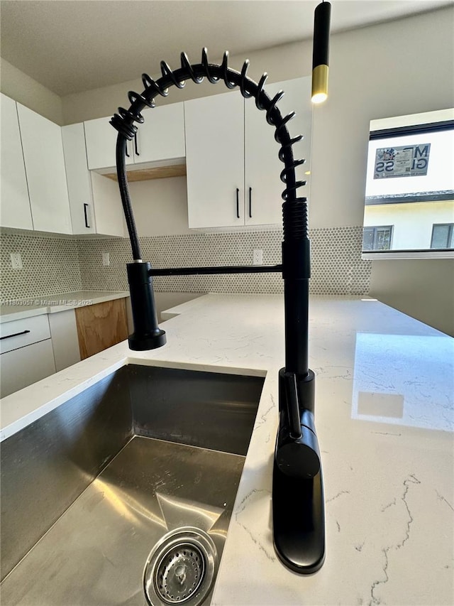 1769 NW 41st St, Miami, FL 33142 - kitchen view of decorative backsplash, white cabinetry, light stone countertops, and a sink