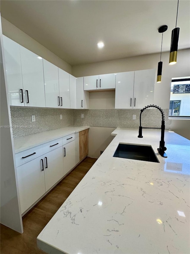 1769 NW 41st St, Miami, FL 33142 - kitchen featuring a sink, light stone counters, white cabinetry, backsplash, and decorative light fixtures