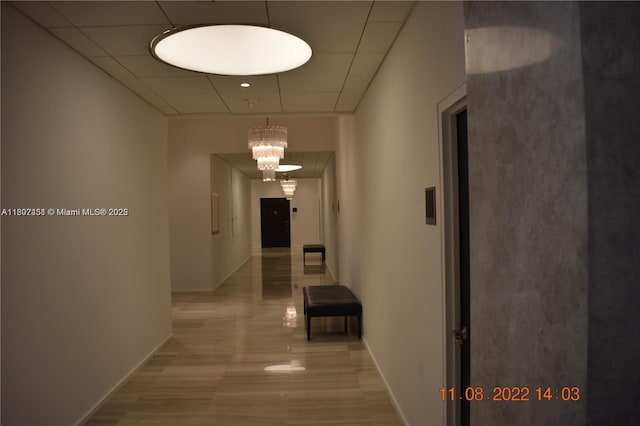 100 Bayview Dr Unit 309, Sunny Isles Beach, FL 33160 - corridor with baseboards, a drop ceiling, and a chandelier