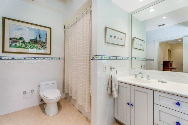 full bath featuring tile walls, toilet, vanity, tile patterned floors, and wainscoting