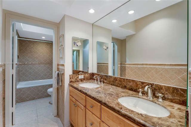 bathroom with tile patterned flooring, double vanity, recessed lighting, toilet, and tiled shower / bath