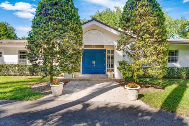 property entrance featuring stucco siding and a yard