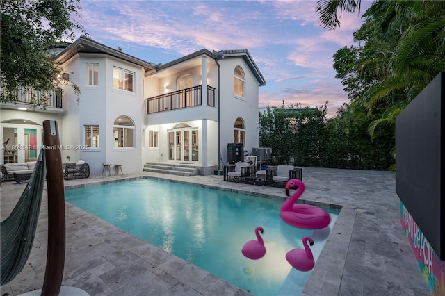 5978 Alton Rd, Miami Beach, FL 33140 - back of house at dusk with a balcony, french doors, a patio area, and stucco siding