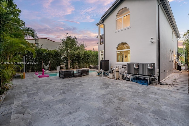 5978 Alton Rd, Miami Beach, FL 33140 - back of property at dusk with stucco siding, a patio, and central AC