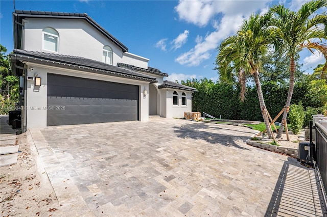 5978 Alton Rd, Miami Beach, FL 33140 - view of front facade featuring stucco siding, decorative driveway, a garage, and a tile roof