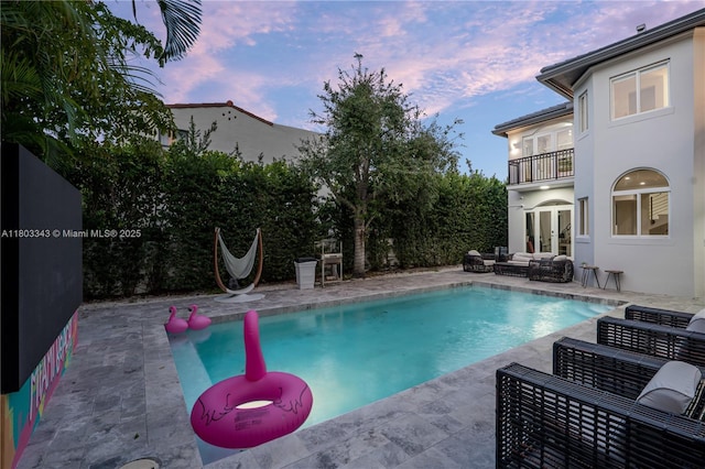 5978 Alton Rd, Miami Beach, FL 33140 - pool at dusk with french doors, an outdoor hangout area, a patio, and fence