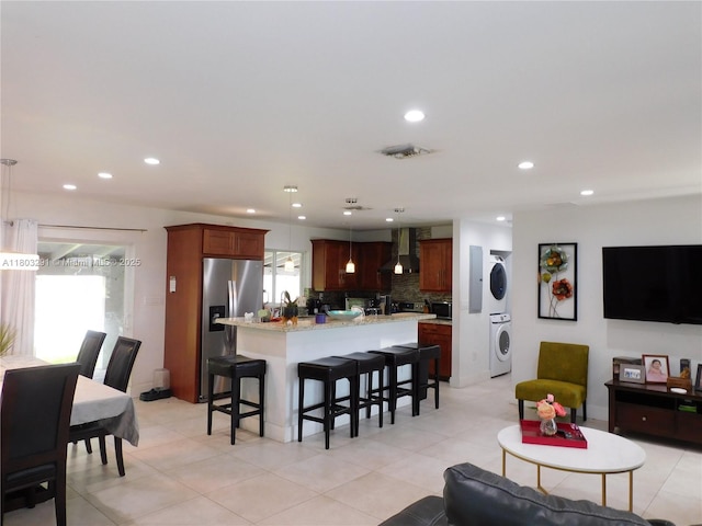 living area featuring stacked washer / drying machine, recessed lighting, and light tile patterned floors