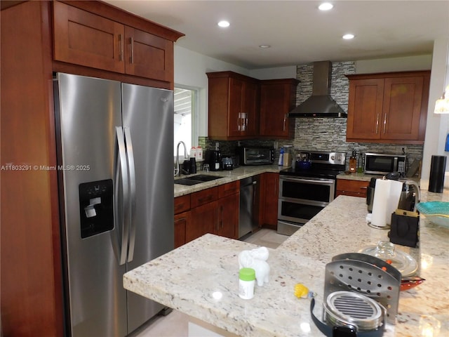 kitchen with appliances with stainless steel finishes, wall chimney range hood, a sink, tasteful backsplash, and recessed lighting