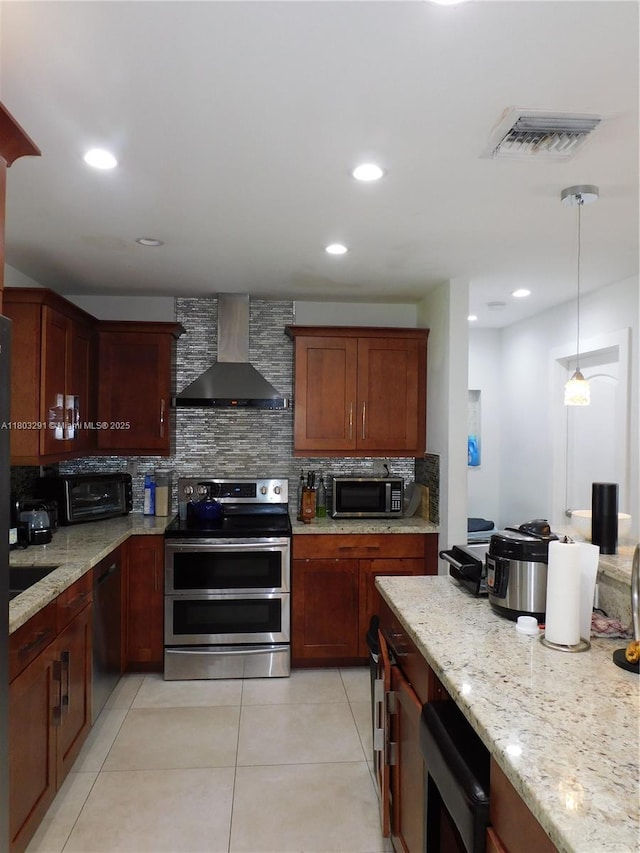 kitchen with wall chimney exhaust hood, appliances with stainless steel finishes, backsplash, light stone counters, and light tile patterned floors