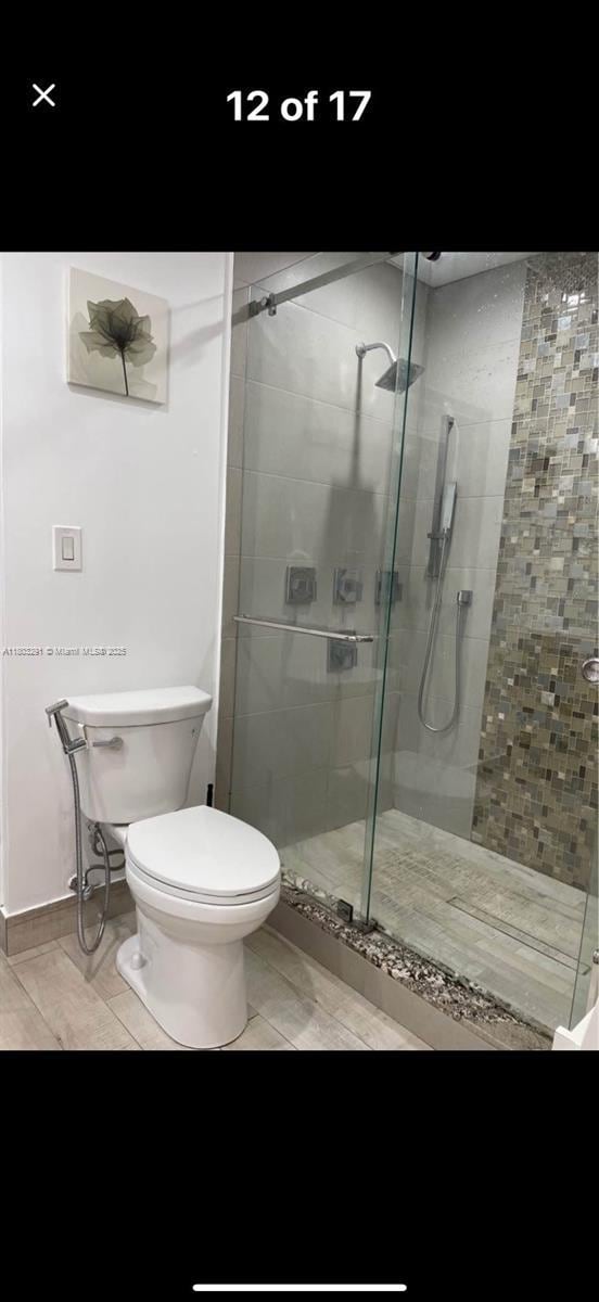 full bathroom with a shower stall, toilet, and tile patterned floors