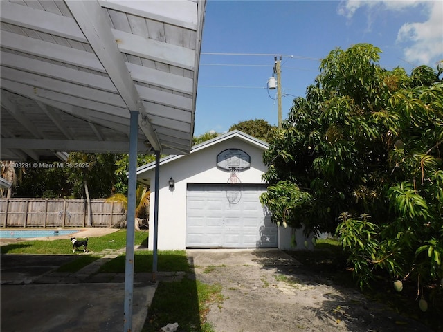 detached garage featuring fence and driveway