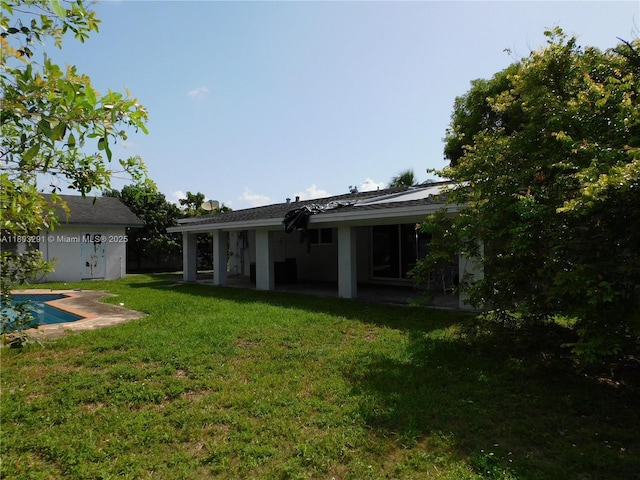 back of property with a patio, a yard, and an outdoor pool