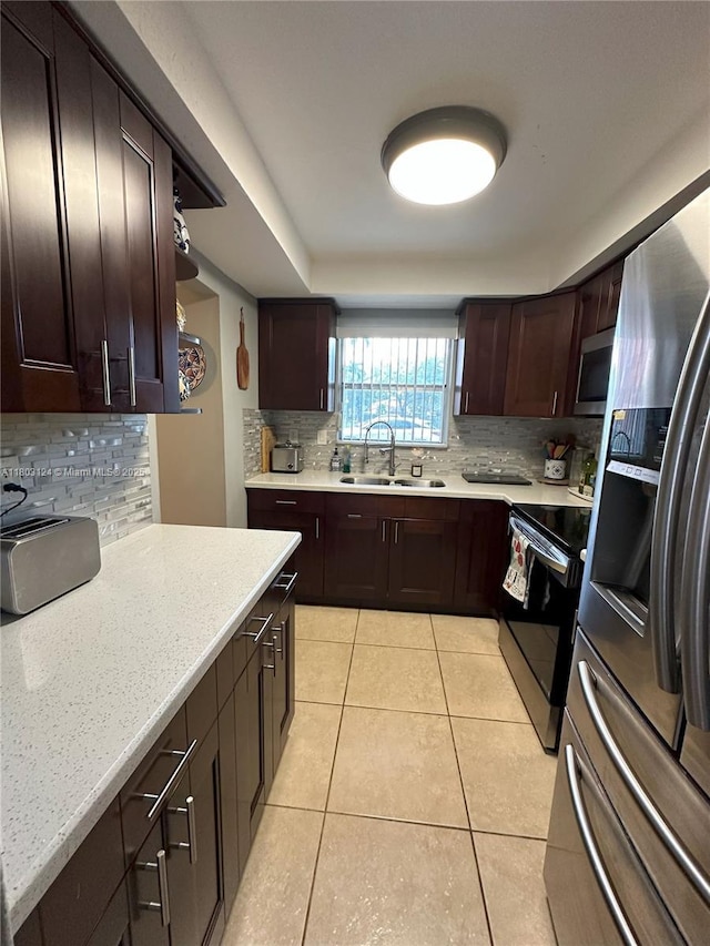 13707 Kendale Lakes Cir Unit 110, Miami, FL 33183 - kitchen with stainless steel appliances, tasteful backsplash, dark brown cabinetry, light tile patterned flooring, and light stone counters