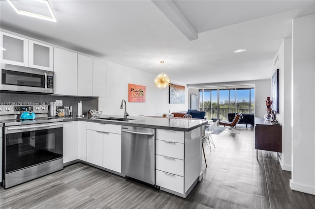 1780 NE 191st St Unit 501-2, Miami, FL 33179 - kitchen featuring stainless steel appliances, open floor plan, a peninsula, dark countertops, and modern cabinets