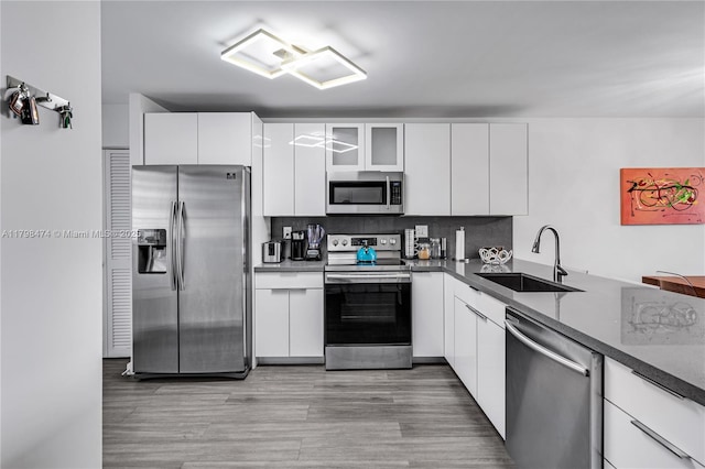 1780 NE 191st St Unit 501-2, Miami, FL 33179 - kitchen featuring stainless steel appliances, a sink, backsplash, white cabinets, and light wood-style flooring
