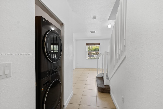 9153 SW 227th St Unit 3, Cutler Bay, FL 33190 - laundry room featuring estacked washer and dryer, light tile patterned flooring, a textured wall, a textured ceiling, and baseboards
