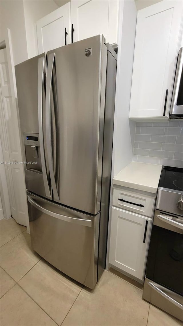 10670 SW 156th Pl Unit 313, Miami, FL 33196 - kitchen with appliances with stainless steel finishes, white cabinetry, light tile patterned flooring, light countertops, and decorative backsplash