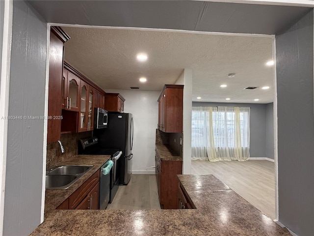 1345 NE 199th St, Miami, FL 33179 - kitchen featuring a sink, appliances with stainless steel finishes, glass insert cabinets, light wood-style flooring, and a textured ceiling