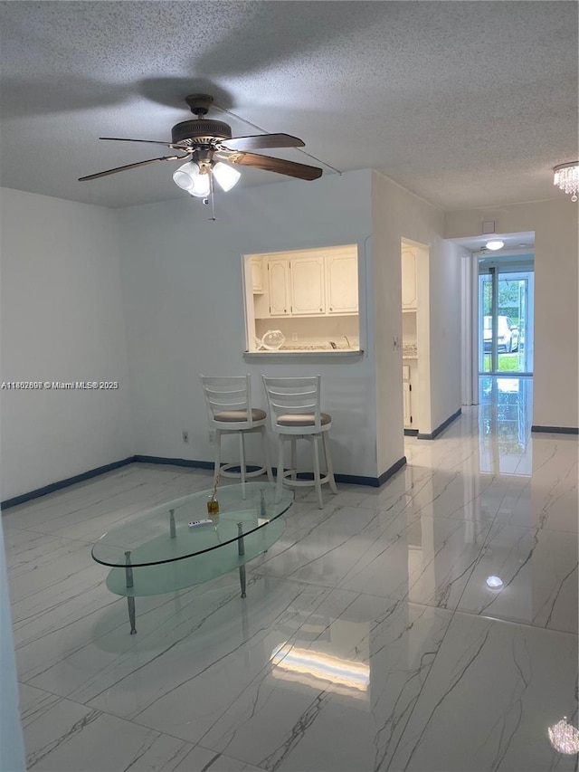 111 Tilford F Unit 111, Deerfield Beach, FL 33442 - unfurnished living room with light marble finish flooring, a textured ceiling, baseboards, and a ceiling fan