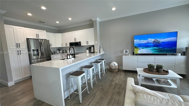 1192 Chinaberry Dr, Weston, FL 33327 - kitchen featuring stainless steel appliances, a kitchen bar, wood finished floors, recessed lighting, and white cabinets