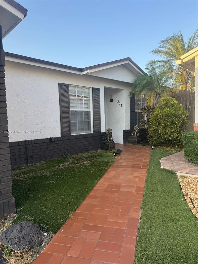 19321 NW 83rd Ave, Hialeah, FL 33015 - doorway to property with stucco siding and a lawn