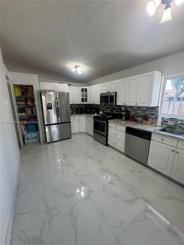 19321 NW 83rd Ave, Hialeah, FL 33015 - kitchen featuring stainless steel appliances, light marble finish floors, a sink, a textured ceiling, and white cabinetry