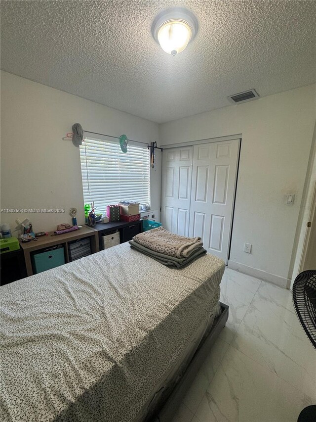 19321 NW 83rd Ave, Hialeah, FL 33015 - bedroom with light marble finish flooring, a textured ceiling, and a closet