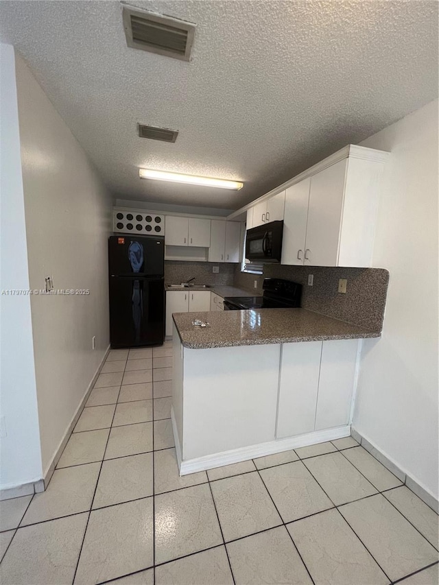 8170 NW 10th St Unit 2, Miami, FL 33126 - kitchen with black appliances, a textured ceiling, a peninsula, light tile patterned floors, and white cabinets