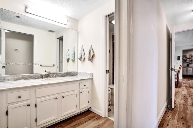 2679 S Ocean Blvd Unit 2B, Boca Raton, FL 33432 - bathroom with a textured ceiling, wood finished floors, toilet, vanity, and baseboards