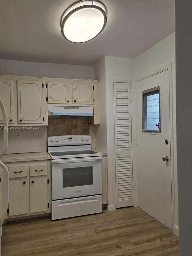1201 NE 191st St Unit G211, Miami, FL 33179 - kitchen with white range with electric stovetop, under cabinet range hood, light countertops, backsplash, and light wood-style flooring