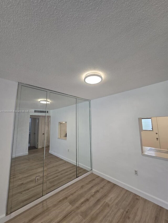 1201 NE 191st St Unit G211, Miami, FL 33179 - unfurnished bedroom with wood finished floors, a closet, a textured ceiling, and baseboards