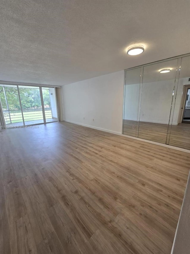 1201 NE 191st St Unit G211, Miami, FL 33179 - empty room with wood finished floors, a textured ceiling, and baseboards