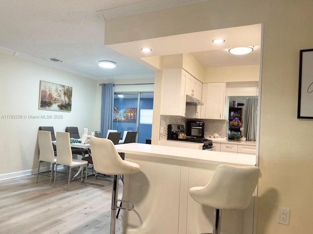 11360 NW 31st St, Sunrise, FL 33323 - kitchen with range, under cabinet range hood, a kitchen bar, white cabinetry, and ornamental molding