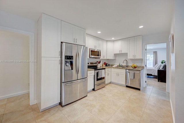 932 Polk St, Hollywood, FL 33019 - kitchen with appliances with stainless steel finishes, a sink, white cabinets, recessed lighting, and light stone counters