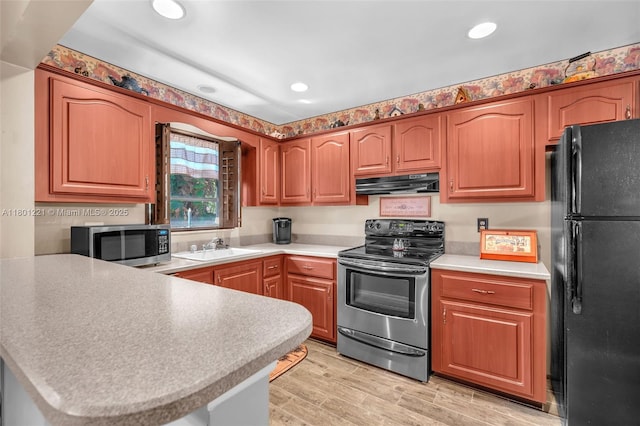 kitchen with stainless steel appliances, under cabinet range hood, a sink, a peninsula, and light countertops