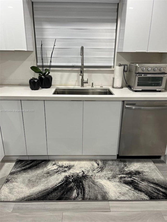 3195 W 10th Ave, Hialeah, FL 33012 - kitchen featuring stainless steel dishwasher, a sink, white cabinetry, and modern cabinets